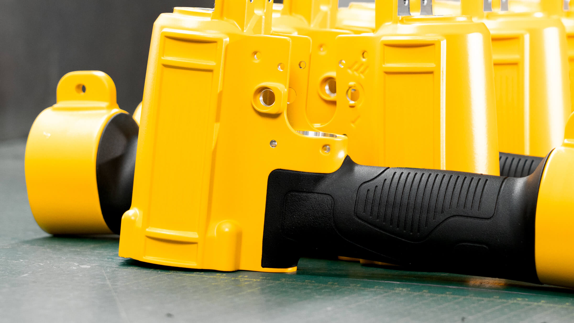 Ergonomic black TPR insert molding on a yellow aluminum die cast pneumatic tool housing, providing superior grip and vibration absorption.