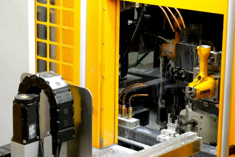 Automated production cell processing overmolded aluminum tool bodies to ensure consistent grip quality and molecular adhesion.