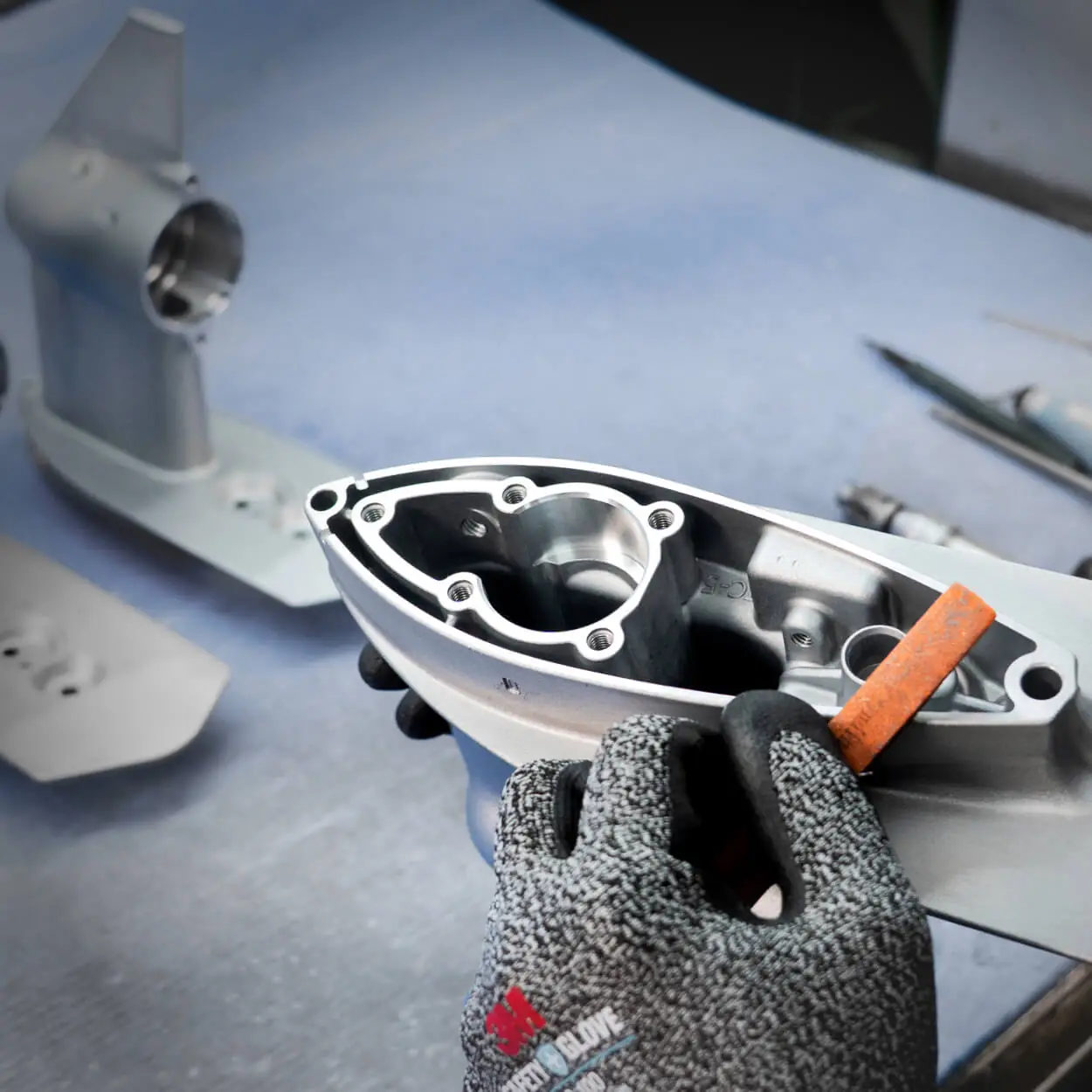 Manual deburring and finishing of a corrosion-resistant ADC-3 aluminum die cast marine component to ensure surface integrity.