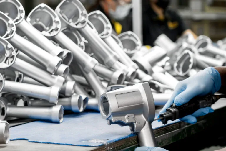 Skilled JoinCast technician performing manual deburring and precision polishing on an aluminum die cast component to ensure a smooth, high-quality surface finish.