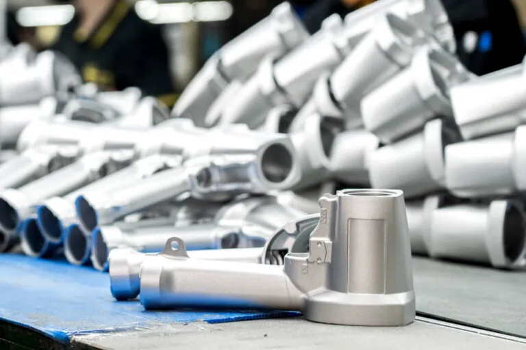 Batch of freshly shot-blasted aluminum die cast components ready for subsequent powder coating or anodizing in a vertically integrated production line.