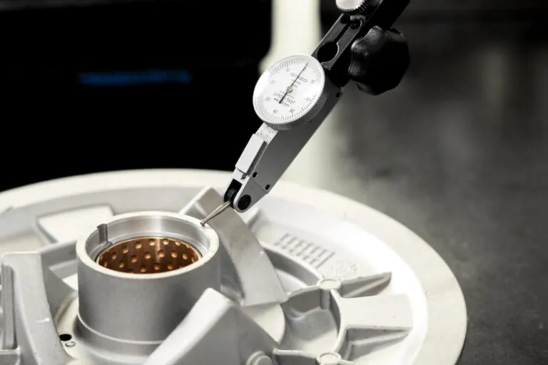 High-precision dial indicator measuring critical bores of an aluminum die casting to ensure strict adherence to ±0.01mm tolerances.