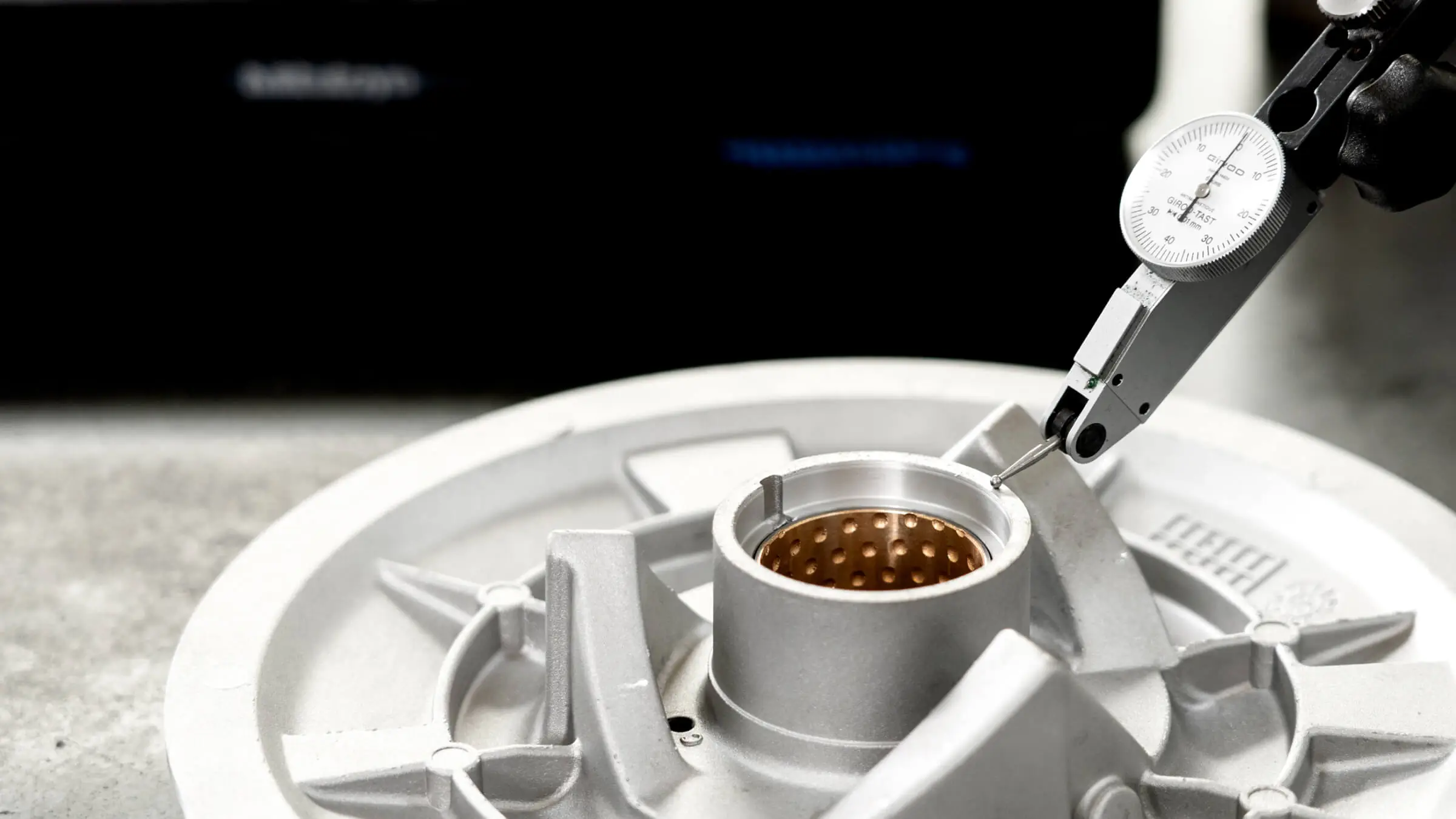 High-precision dial indicator measuring critical bores of an aluminum die casting to ensure strict adherence to ±0.01mm tolerances.