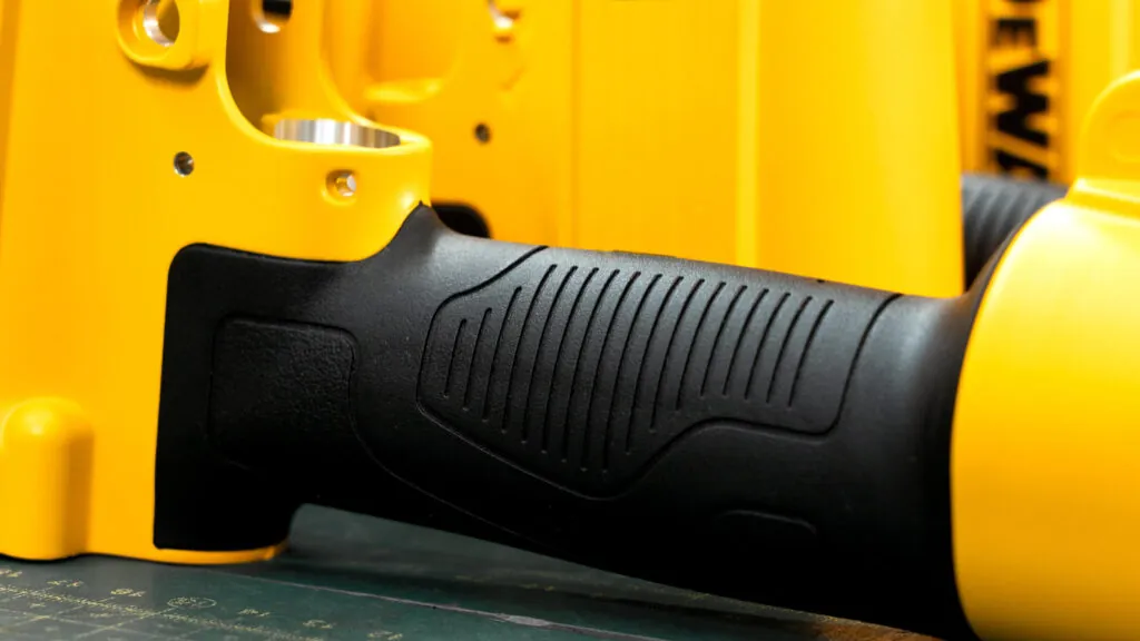 Ergonomic black TPR insert molding on a yellow aluminum die cast pneumatic tool housing, providing superior grip and vibration absorption.